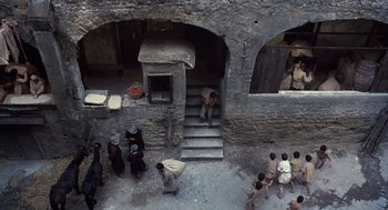 Movie still from “The Decameron” (1971), directed by Pier Paolo Pasolini – A group of people standing on steps in a building; Extreme Wide shot, Overhead angle
