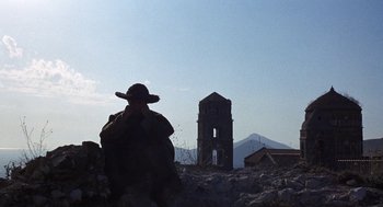 Movie still from “The Decameron” (1971), directed by Pier Paolo Pasolini – A man in a hat is standing in front of a building; Extreme Wide shot, Low angle