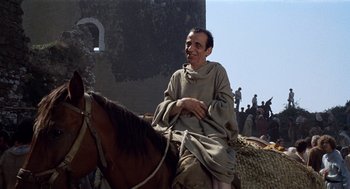 Movie still from “The Decameron” (1971), directed by Pier Paolo Pasolini – A man sitting on top of a brown horse; Medium shot, Over the shoulder angle