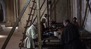 Movie still from “The Decameron” (1971), directed by Pier Paolo Pasolini – A group of people standing around a table; Wide shot, High angle