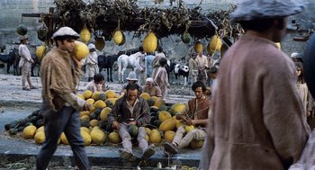 Movie still from “The Decameron” (1971), directed by Pier Paolo Pasolini – A group of people sitting around a pile of fruit; Wide shot, High angle