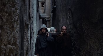 Movie still from “The Decameron” (1971), directed by Pier Paolo Pasolini – A group of people walking down a street; Wide shot, High angle
