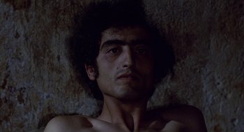 Movie still from “The Decameron” (1971), directed by Pier Paolo Pasolini – A shirtless man laying on the ground in the dark; Close Up shot, Overhead angle