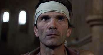 Movie still from “The Decameron” (1971), directed by Pier Paolo Pasolini – A person wearing a bandage on his head; Close Up shot, Low angle