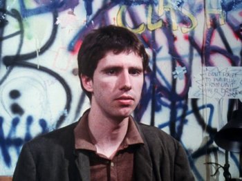 Movie still from “The Decline of Western Civilization” (1981), directed by Penelope Spheeris – A man standing in front of a wall covered in graffiti; Close Up shot, Low angle