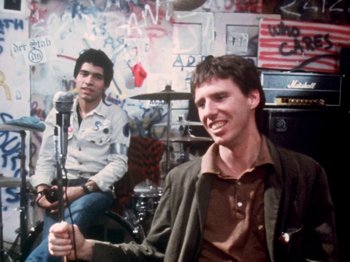 Movie still from “The Decline of Western Civilization” (1981), directed by Penelope Spheeris – Two men sitting in front of microphones in a room; Medium shot, Low angle