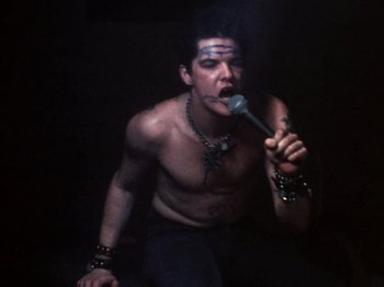 Movie still from “The Decline of Western Civilization” (1981), directed by Penelope Spheeris – A man with a microphone in his mouth; Medium shot, High angle