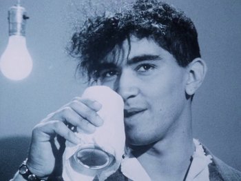 Movie still from “The Decline of Western Civilization” (1981), directed by Penelope Spheeris – A young man drinking a beverage from a cup; Close Up shot, Low angle