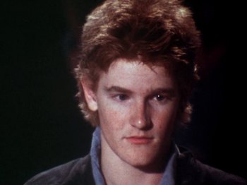 Movie still from “The Decline of Western Civilization” (1981), directed by Penelope Spheeris – A young man with red hair is looking at the camera; Close Up shot, High angle