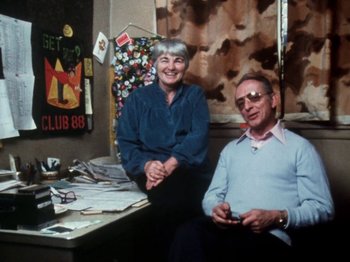 Movie still from “The Decline of Western Civilization” (1981), directed by Penelope Spheeris – An older man and woman sitting at a desk; Medium shot, Low angle
