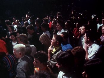Movie still from “The Decline of Western Civilization” (1981), directed by Penelope Spheeris – A crowd of people sitting in a room; Wide shot, High angle