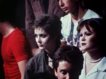 Movie still from “The Decline of Western Civilization” (1981), directed by Penelope Spheeris – A group of people standing next to each other in a room; Medium shot, High angle