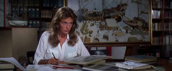 Movie still from “The Deep” (1977), directed by Peter Yates – A woman sitting at a table writing on a piece of paper; Medium shot, High angle