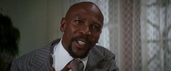 Movie still from “The Deep” (1977), directed by Peter Yates – A man in a suit and tie talking to the camera; Close Up shot, Low angle