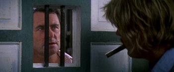 Movie still from “The Deep” (1977), directed by Peter Yates – A man looking into a window while holding a cigarette in his mouth; Close Up shot, Over the shoulder angle