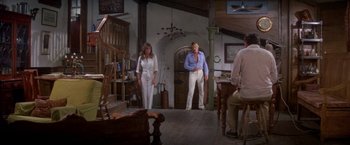 Movie still from “The Deep” (1977), directed by Peter Yates – A man and a woman are standing in a living room; Wide shot, Low angle