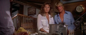 Movie still from “The Deep” (1977), directed by Peter Yates – A man and a woman standing next to each other in a room; Medium shot, Low angle