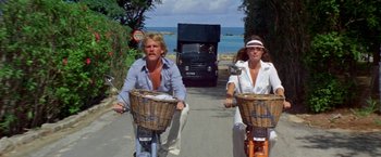 A man and a woman riding bikes down a street