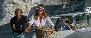 Movie still from “The Deep” (1977), directed by Peter Yates – A woman riding a bike with a basket on the back of it; Medium shot, Low angle