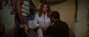 Movie still from “The Deep” (1977), directed by Peter Yates – A woman sitting on the ground with a man; Medium shot, High angle