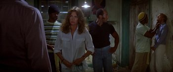 Movie still from “The Deep” (1977), directed by Peter Yates – A woman standing next to two men in a room; Medium shot, Over the shoulder angle