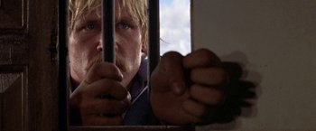 Movie still from “The Deep” (1977), directed by Peter Yates – A person holding a jail cell bar; Close Up shot, Low angle