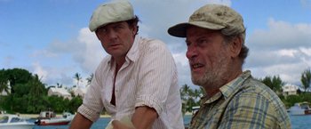 Movie still from “The Deep” (1977), directed by Peter Yates – Two older men standing next to each other on a beach; Close Up shot, Low angle