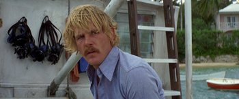 Movie still from “The Deep” (1977), directed by Peter Yates – A man with blonde hair and a blue shirt; Close Up shot, Low angle