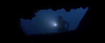 Movie still from “The Deep” (1977), directed by Peter Yates – A scuba diver in a cave with a light shining on him; Wide shot, Overhead angle