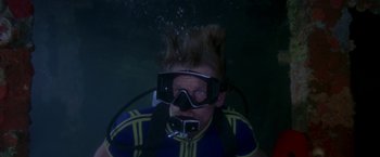 Movie still from “The Deep” (1977), directed by Peter Yates – A man in a wetsuit with goggles and a scuba mask; Medium shot, High angle