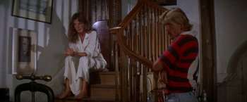 Movie still from “The Deep” (1977), directed by Peter Yates – A woman sitting on the stairs of a house next to a man; Medium shot, High angle