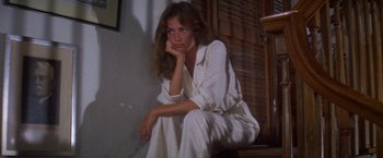 Movie still from “The Deep” (1977), directed by Peter Yates – A woman sitting on the steps of a house wearing pajamas; Medium shot, High angle