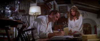 Movie still from “The Deep” (1977), directed by Peter Yates – A man sitting at a table writing on a piece of paper; Medium shot, Low angle