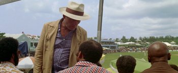 Movie still from “The Deep” (1977), directed by Peter Yates – A man wearing a hat talking to two people; Medium shot, Over the shoulder angle