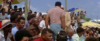 Movie still from “The Deep” (1977), directed by Peter Yates – A group of men standing next to each other on a field; Medium shot, Over the shoulder angle