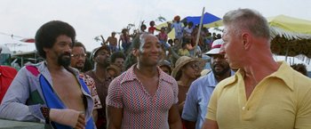 Movie still from “The Deep” (1977), directed by Peter Yates – A group of people standing in front of a crowd of onlookers; Medium shot, Low angle