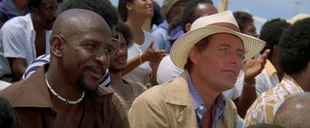 Movie still from “The Deep” (1977), directed by Peter Yates – A group of people sitting in a crowd of people wearing hats; Close Up shot, Over the shoulder angle