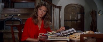Movie still from “The Deep” (1977), directed by Peter Yates – A woman sitting at a table with a plate of food in front of her; Medium shot, High angle