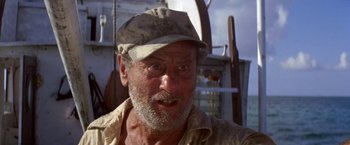 Movie still from “The Deep” (1977), directed by Peter Yates – An older man wearing a hat and looking at the camera; Close Up shot, Low angle