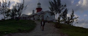 Movie still from “The Deep” (1977), directed by Peter Yates – A man standing in front of a light house; Extreme Wide shot, Low angle