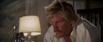 Movie still from “The Deep” (1977), directed by Peter Yates – A person wearing a white shirt near a lamp; Close Up shot, Low angle