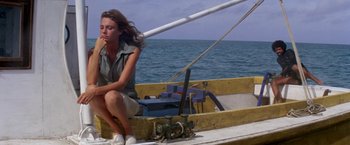 Movie still from “The Deep” (1977), directed by Peter Yates – A woman sitting on the bow of a small boat; Wide shot, High angle