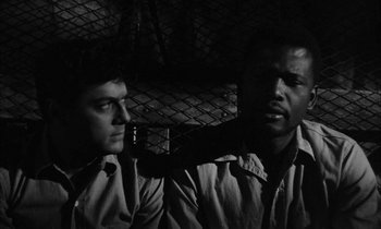 Movie still from “The Defiant Ones” (1958), directed by Stanley Kramer – A black and white photo of two men standing next to each other; Close Up shot, Over the shoulder angle