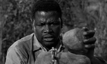 Movie still from “The Defiant Ones” (1958), directed by Stanley Kramer – A black and white photo of a man holding a rock; Close Up shot, High angle