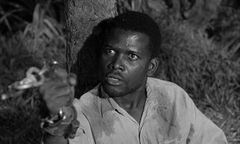 Movie still from “The Defiant Ones” (1958), directed by Stanley Kramer – A black and white photo of a man holding a knife; Close Up shot, Low angle