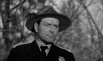 Movie still from “The Defiant Ones” (1958), directed by Stanley Kramer – A man wearing a hat and a police uniform; Close Up shot, Low angle