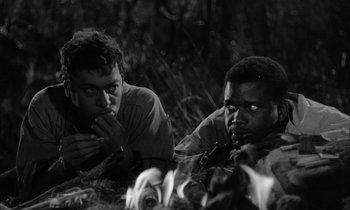 Movie still from “The Defiant Ones” (1958), directed by Stanley Kramer – A black and white photo of two men sitting in the grass; Close Up shot, High angle