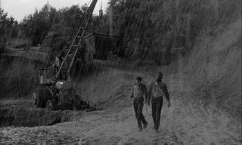 Movie still from “The Defiant Ones” (1958), directed by Stanley Kramer – Two men walking on a dirt road in the rain; Wide shot, High angle