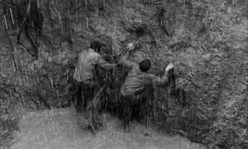 Movie still from “The Defiant Ones” (1958), directed by Stanley Kramer – Two men climbing a rock wall in the rain; Wide shot, Overhead angle