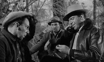 Movie still from “The Defiant Ones” (1958), directed by Stanley Kramer – A group of men standing next to each other on a cell phone; Medium shot, Over the shoulder angle